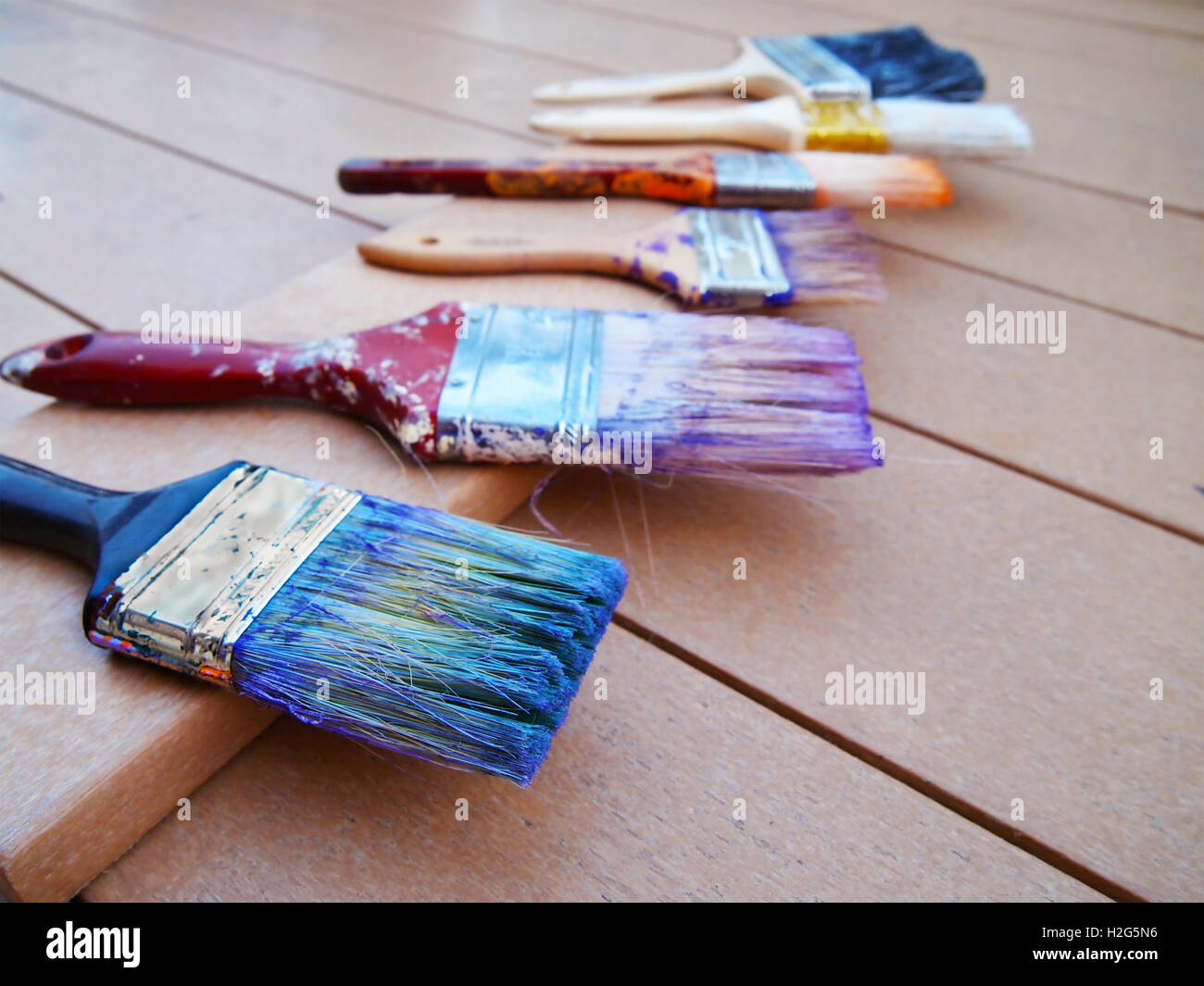 Une ligne de pinceaux colorés, utilisés dans diverses couleurs sèchent sur une plate-forme après un projet de peinture de la chambre. Banque D'Images
