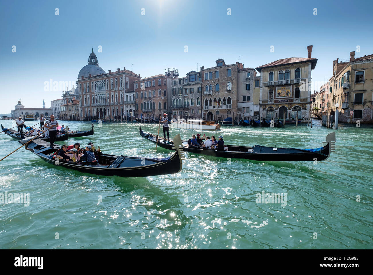 Trois gondoles de touristes sur le Grand Canal à Venise en Italie à la fin de l'été en face de bâtiments typiques de Venise Banque D'Images