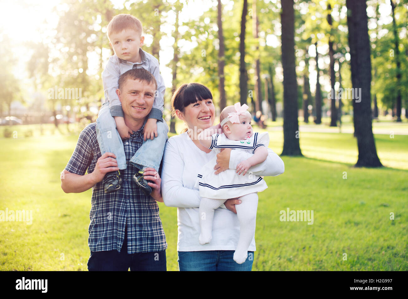 Jeune famille avec deux enfants de marcher dans un parc d'été Banque D'Images