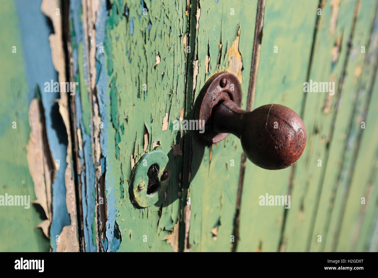Ancienne poignée de porte en métal rouillé sur une porte avec de la peinture. Banque D'Images
