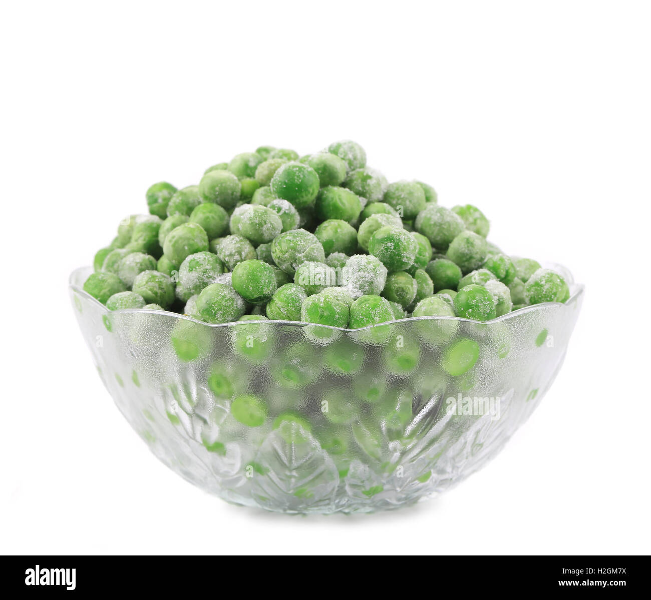 Plat en verre vert avec petits pois congelés. Banque D'Images