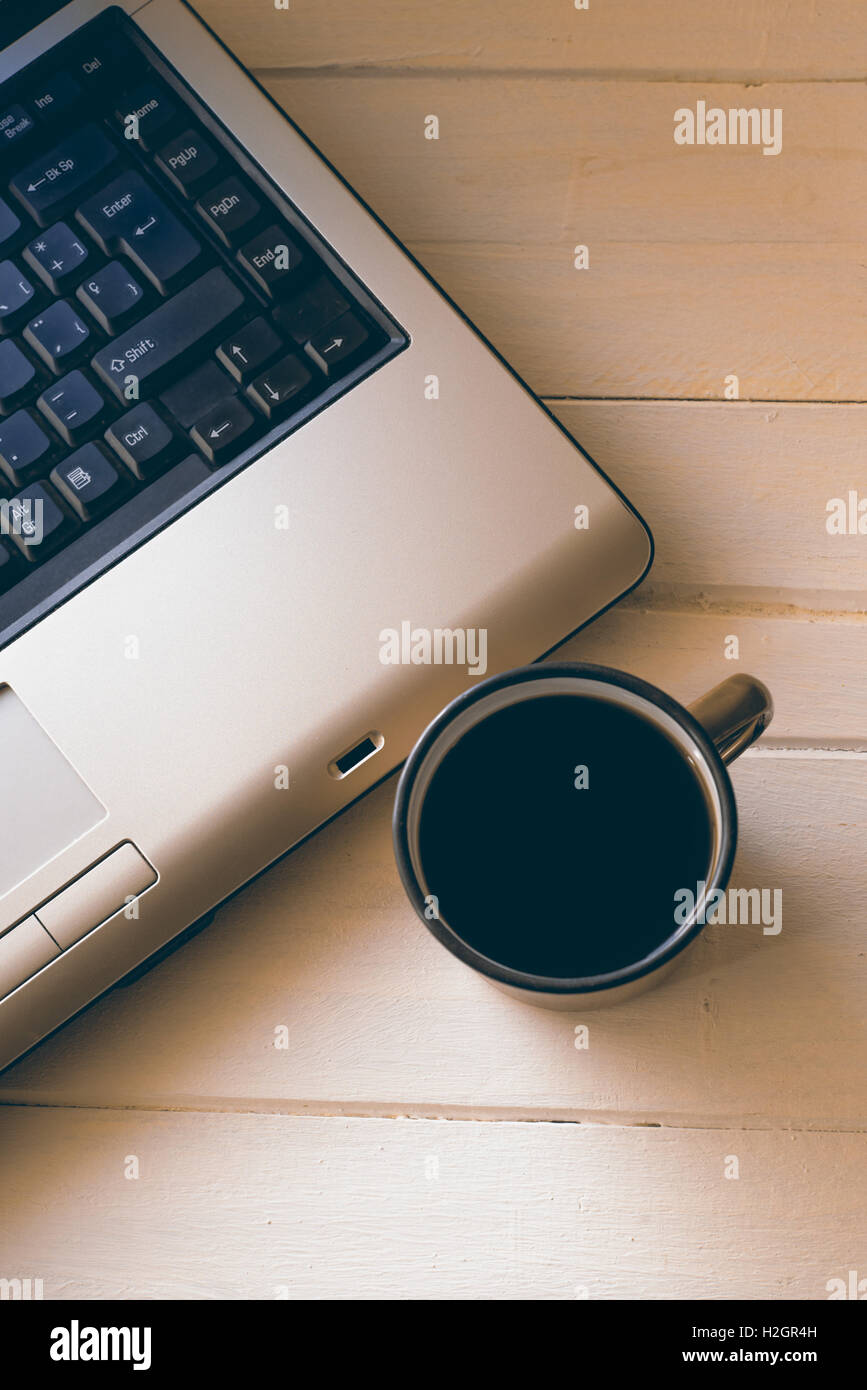 Tasse de café et un ordinateur portable sur une table en bois blanc Banque D'Images