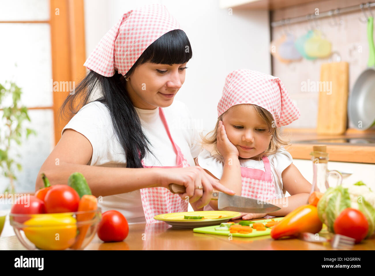 L'enseignement de mère enfant faisant salade en cuisine. Maman et enfant hacher les légumes sur une planche à découper avec couteau. Concept de cuisson de ha Banque D'Images