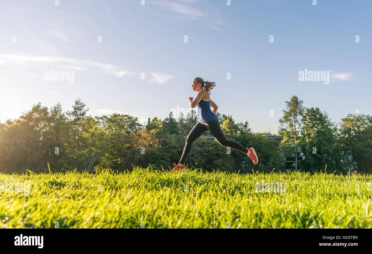 Jeune femme dans les vêtements de sport jogging en Park, Munich, Haute-Bavière, Bavière, Allemagne Banque D'Images