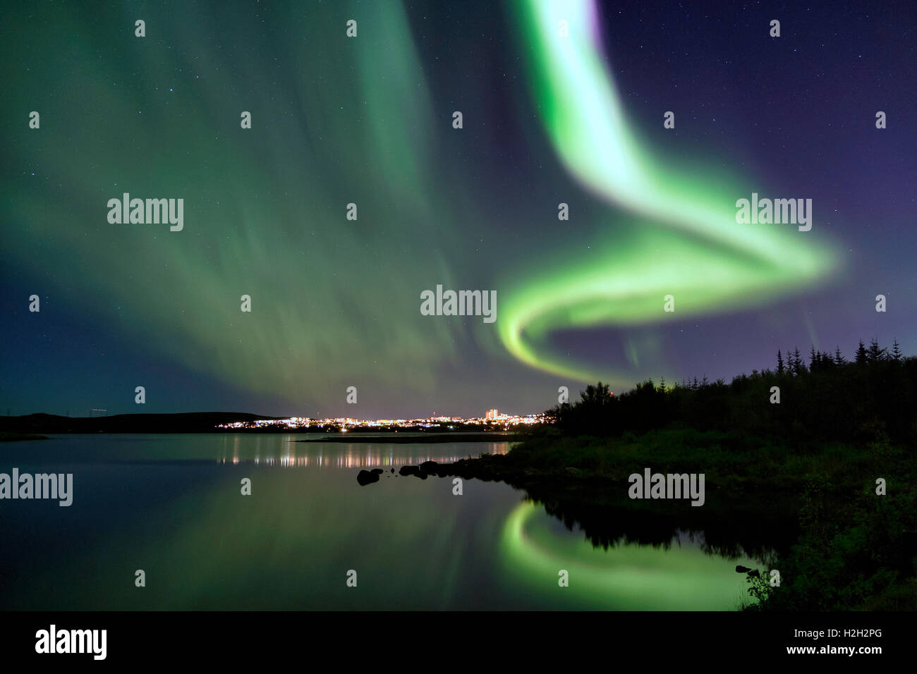 Les Aurora plus Eillidavatn près de Reykjavik en Islande. eau calme reflétant les aurores boréales dans le ciel flamboyant. Banque D'Images