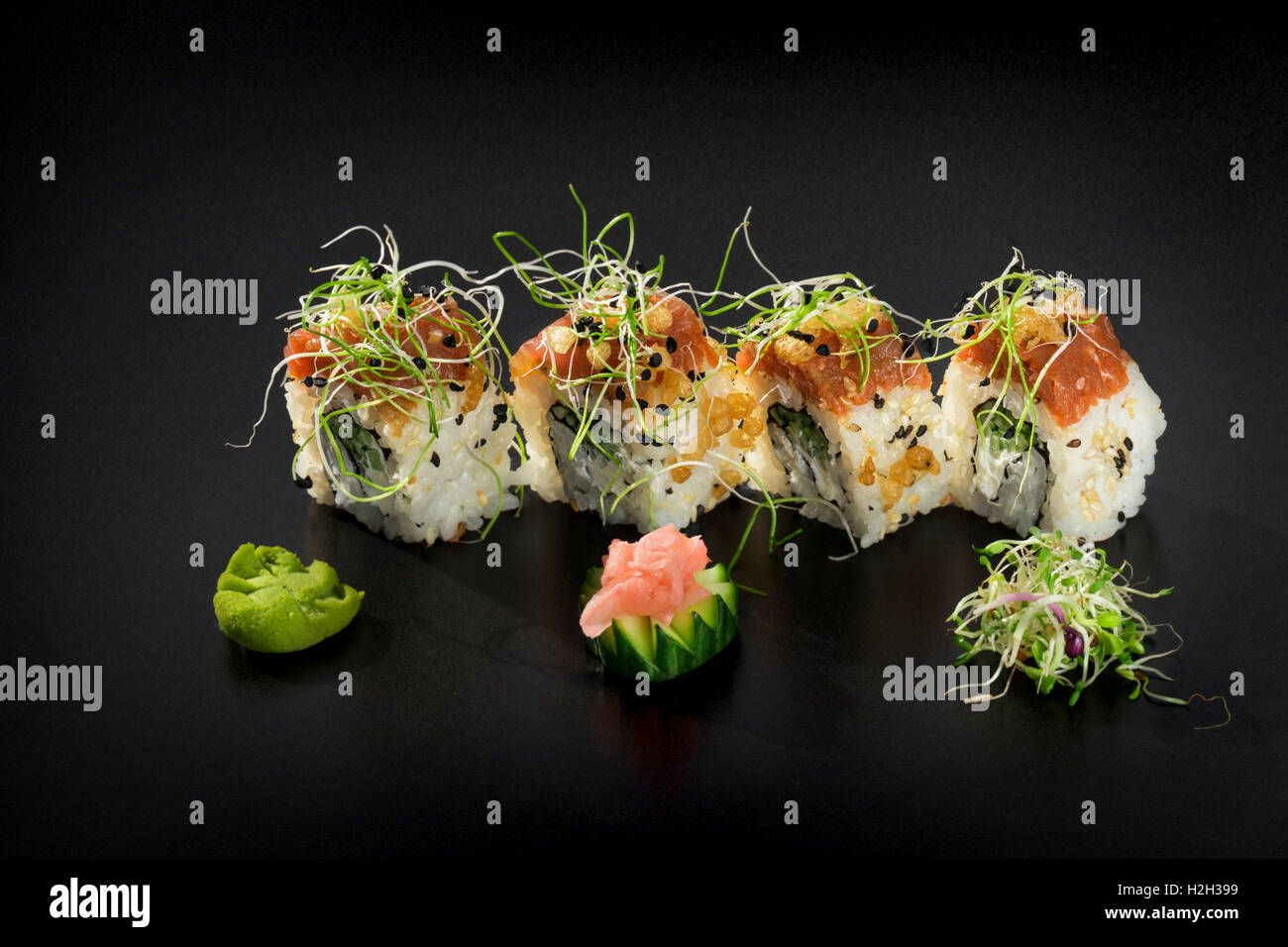 Uramaki sushi maki frais roule sur fond noir Banque D'Images