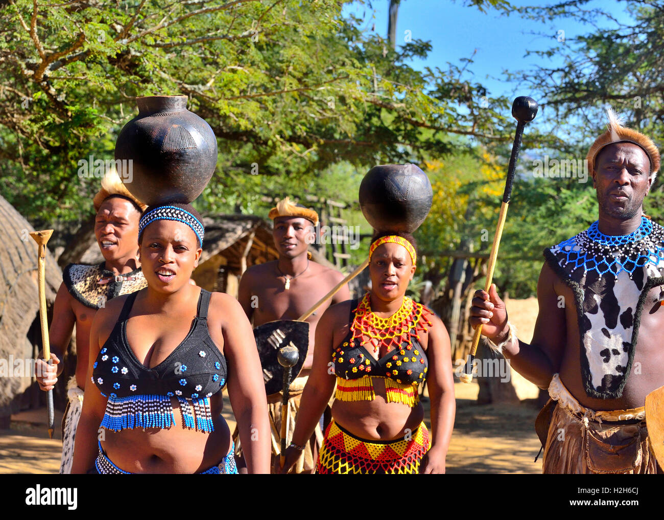 Troupe Zulu avec des jeunes filles portant des bols à eau lors d'une représentation Zulu Experience au Shakaland Cultural Village, Eshowe, Afrique du Sud Banque D'Images