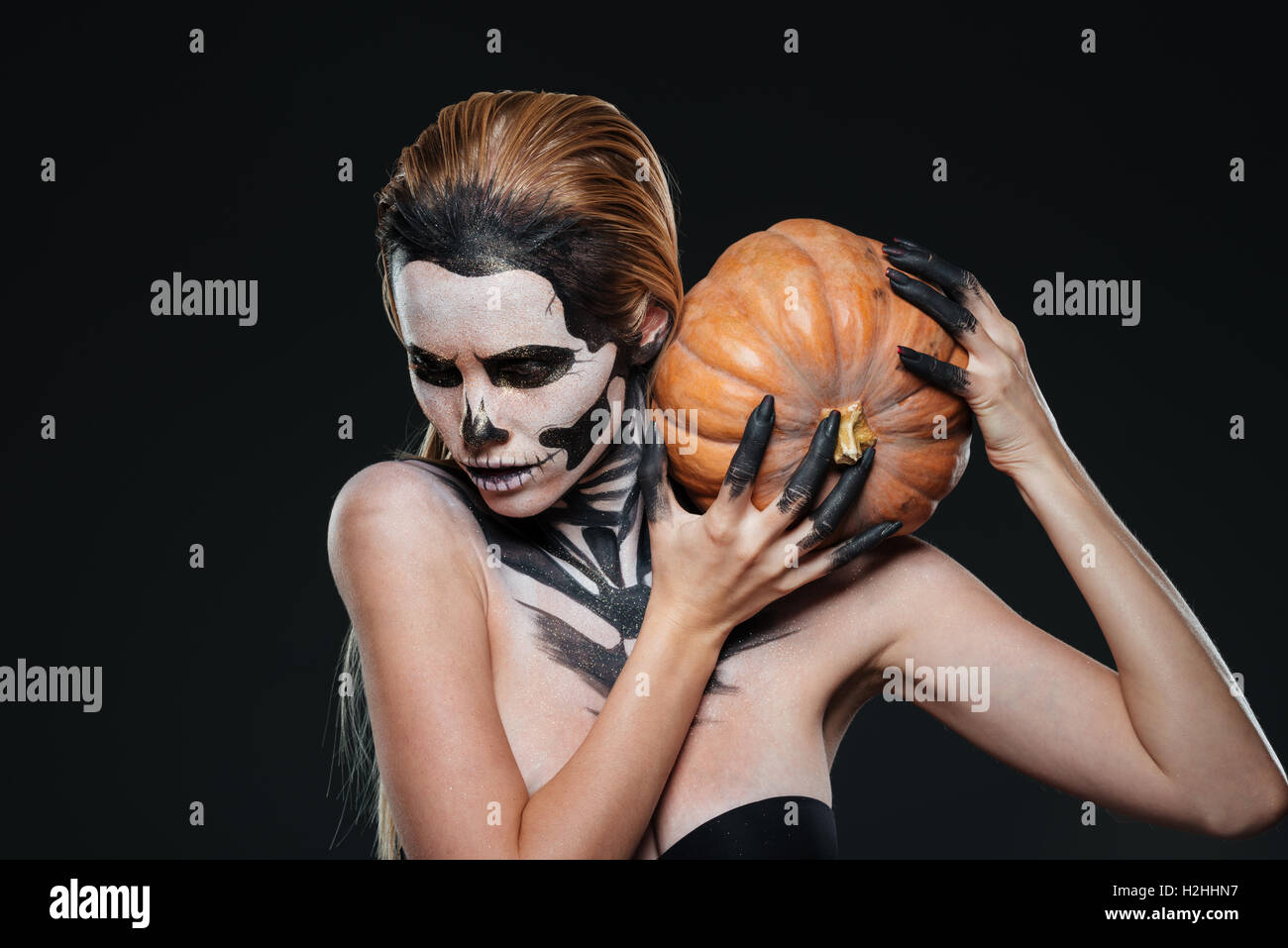 Femme avec peur maquillage halloween citrouille holding sur fond noir Banque D'Images