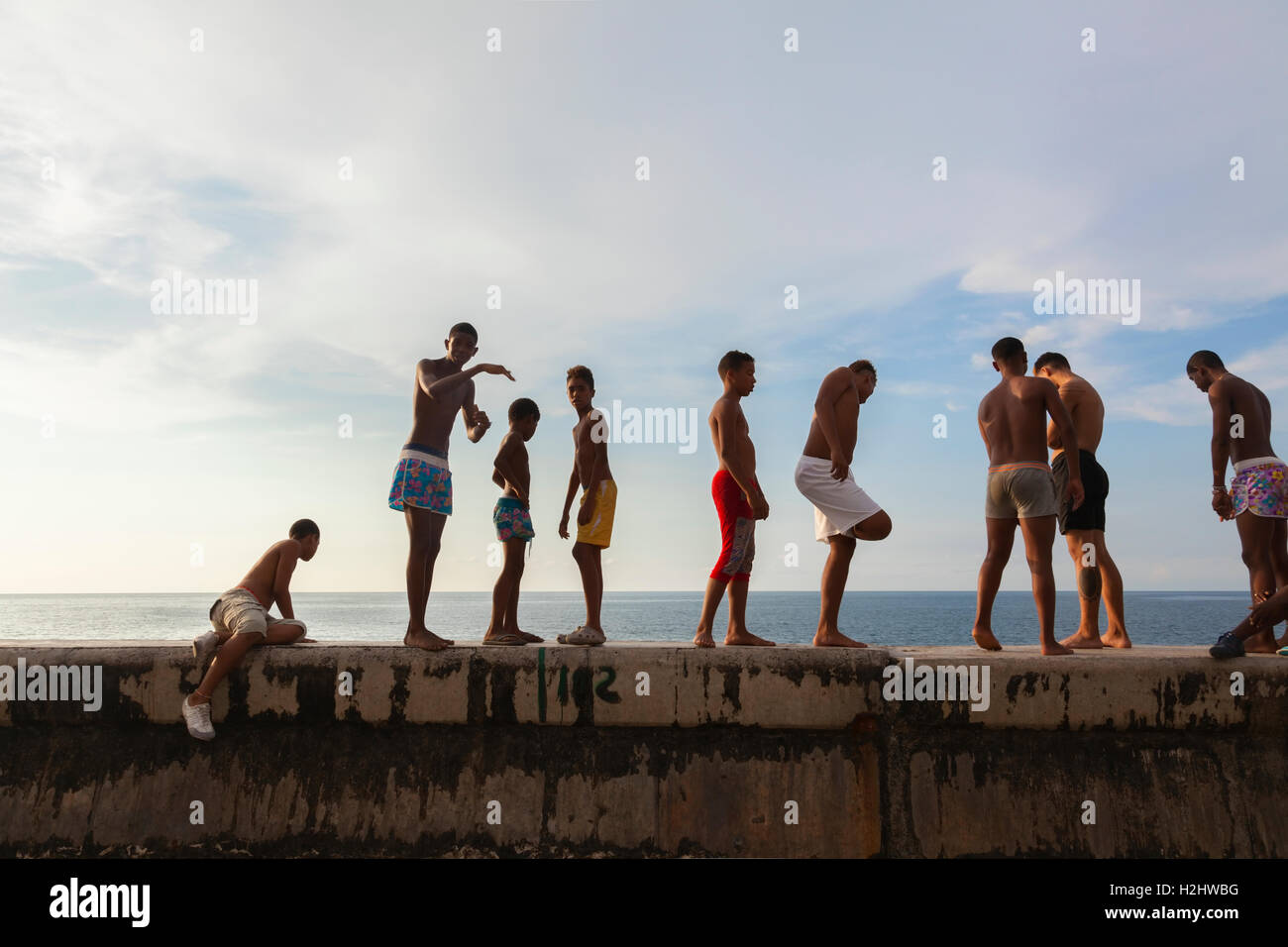 Les enfants dans leurs maillots de bain debout le long de la digue sur le point d'aller nager le long du Malecón dans le centre de La Havane, Cuba. Banque D'Images