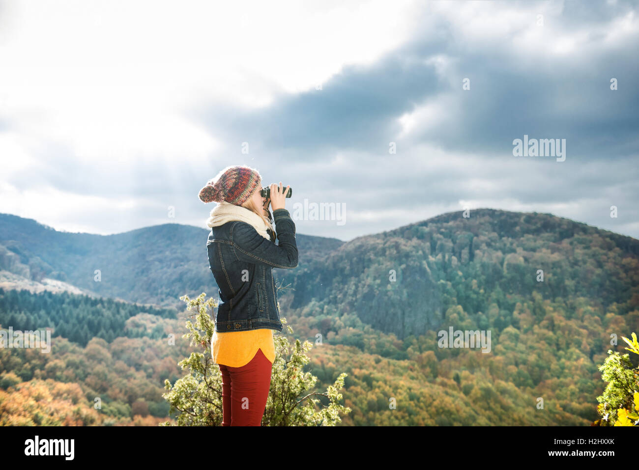 Belle femme regardant à travers des jumelles, l'automne ensoleillé coloré Banque D'Images