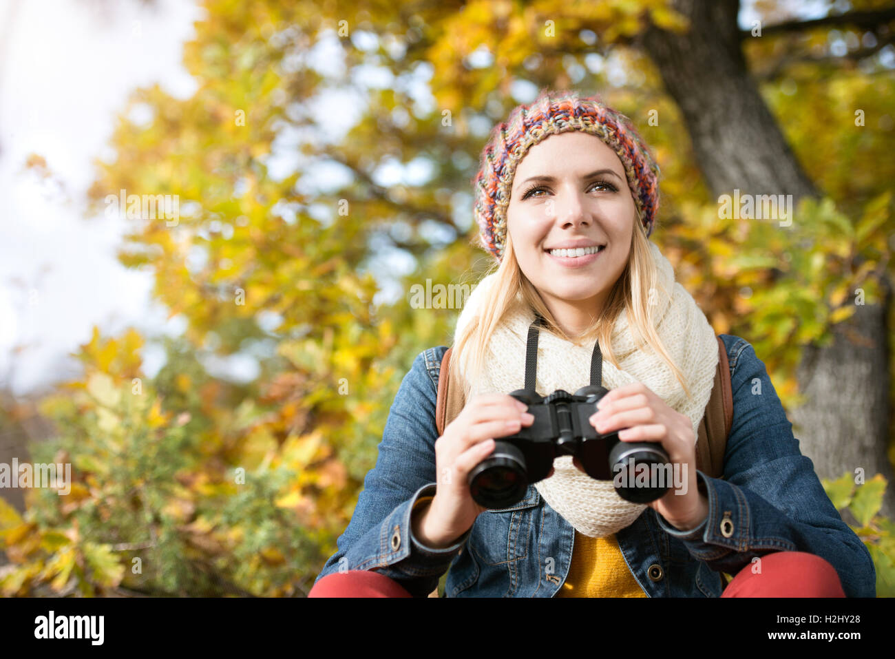 Belle Jeune femme tenant des jumelles, l'automne ensoleillé coloré Banque D'Images