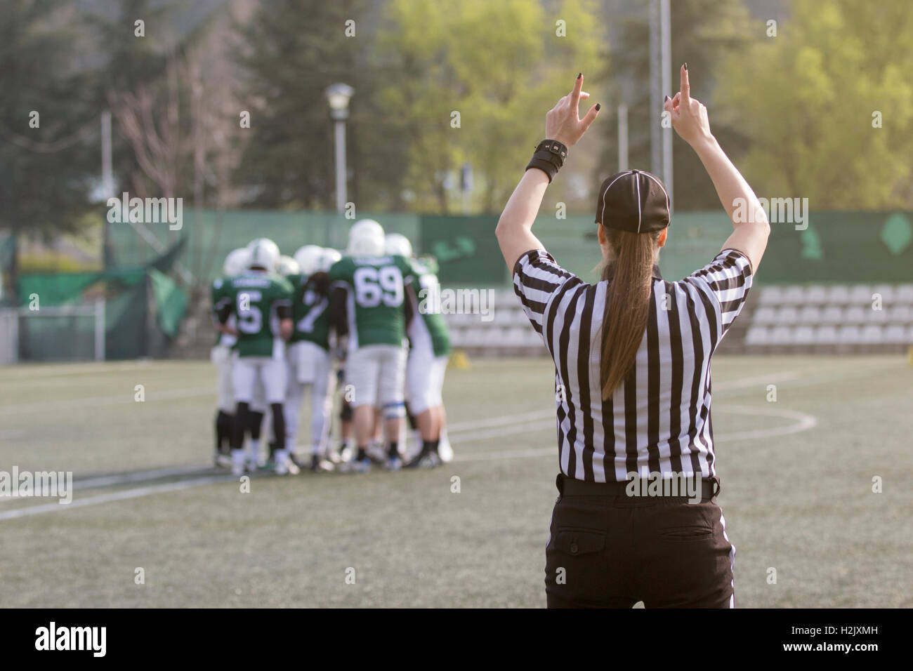 Le football féminin en juge dépouillé chemises noir et blanc sur le terrain. Joueurs en maillots verts et blancs à l'arrière-plan Banque D'Images