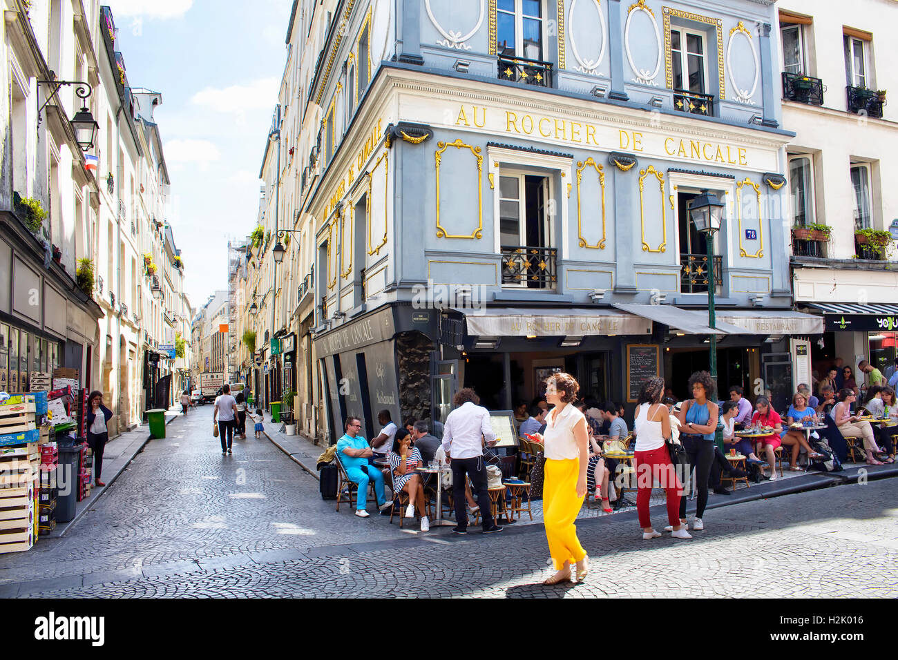 Femme française passe par un café/bistro où les gens ont le déjeuner sur la Rue Montorgueil à Paris. Banque D'Images