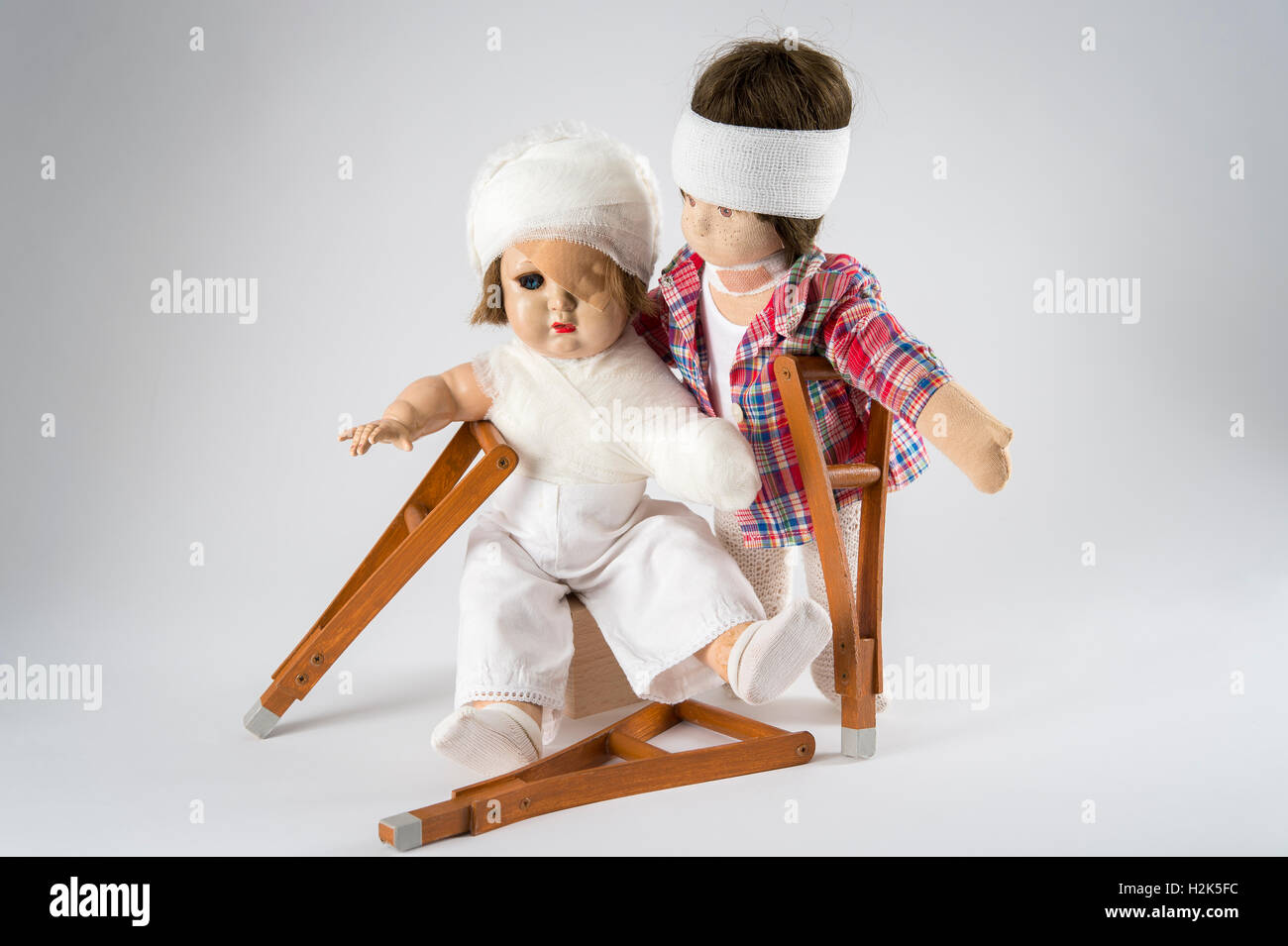 Deux poupées, des bandages sur la tête, œil, bras et l'épaule bandage, NECK BRACE, béquilles, fond blanc Banque D'Images