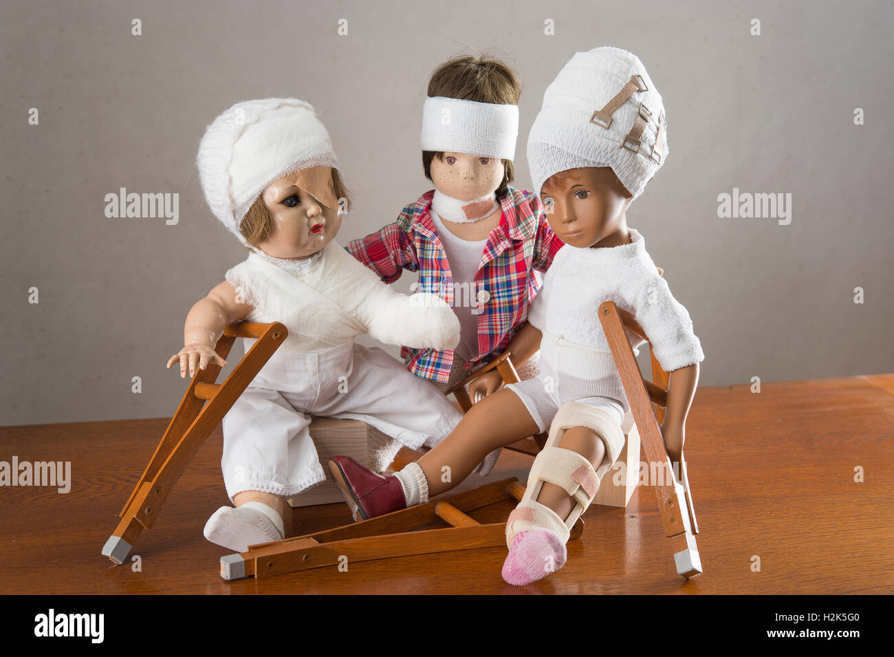 Trois poupées assis, des bandages sur la tête, la jambe d'une attelle, béquilles, eye patch, bras et l'épaule bandage, neck brace Banque D'Images