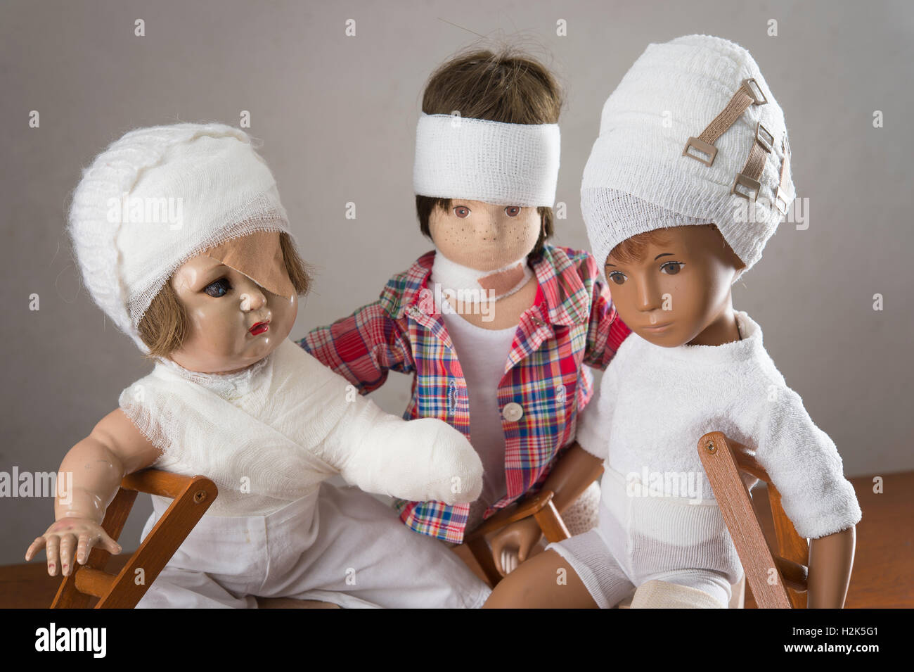 Trois poupées assis, des bandages sur la tête, la jambe d'une attelle, béquilles, eye patch, bras et l'épaule bandage, neck brace Banque D'Images