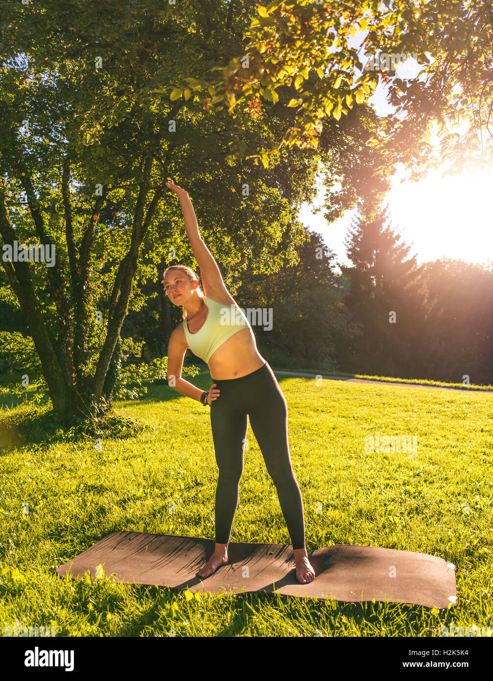 Exercice d'échauffement, young woman in sportswear faisant d'entraînement sur le tapis de parc, Munich, Haute-Bavière, Bavière, Allemagne Banque D'Images