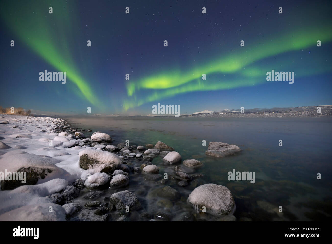 Les aurores boréales au-dessus d'un fjord au clair de lune, dans le nord de la Norvège en hiver. Banque D'Images