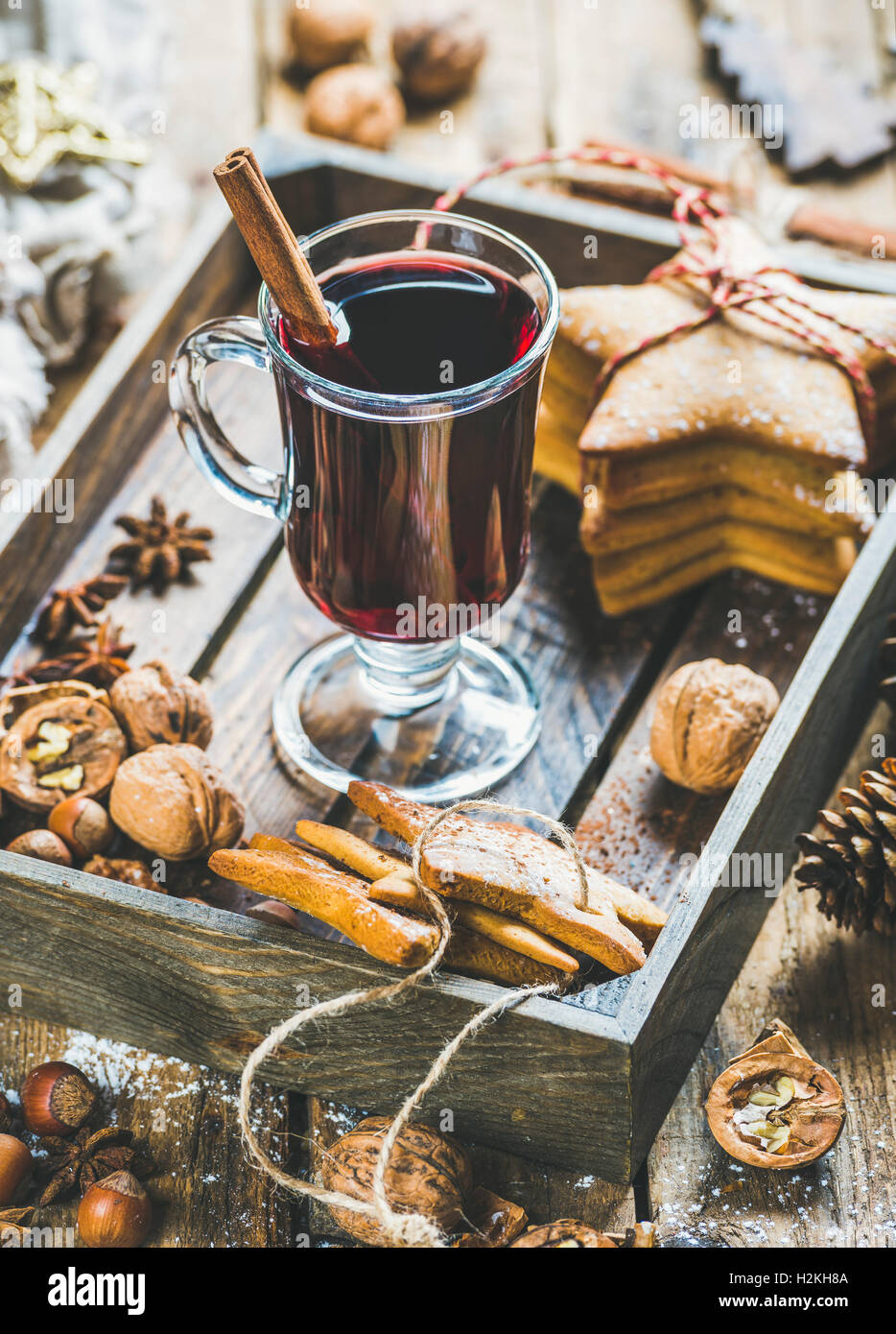 Verre de vin chaud en plateau en bois avec Noël gingerbread cookies, les noix, la cannelle, l'anis et des pommes de pin rustique en bois plus Banque D'Images