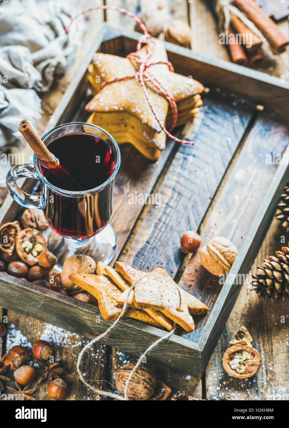Verre de vin chaud en plateau en bois avec Noël gingerbread cookies, les noix, la cannelle, l'anis et des pommes de pin rustique en bois plus Banque D'Images