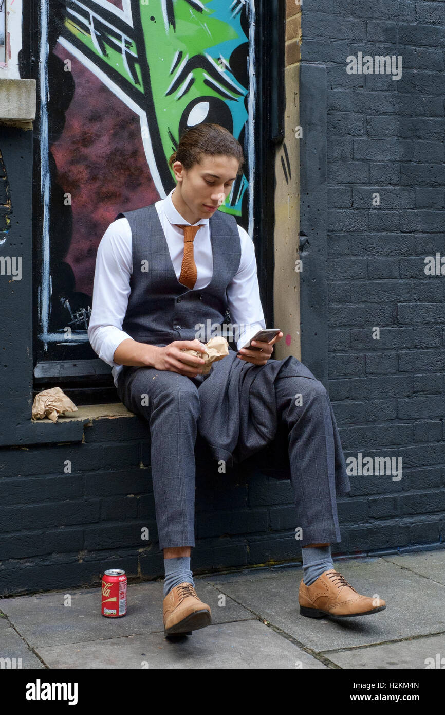 Jeune homme bien habillé et porter un costume de manger le déjeuner dans  une ruelle couverte de graffiti en zone urbaine uk Photo Stock - Alamy