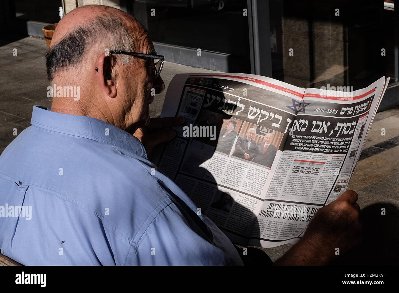 Jérusalem, Israël. 30 Septembre, 2016. Un homme lit un journal hébreu quotidien informant de Mahmoud Abbas, Abu Mazen, participation à la cérémonie funèbre pour l'ancien président israélien Shimon Peres. Credit : Alon Nir/Alamy Live News Banque D'Images