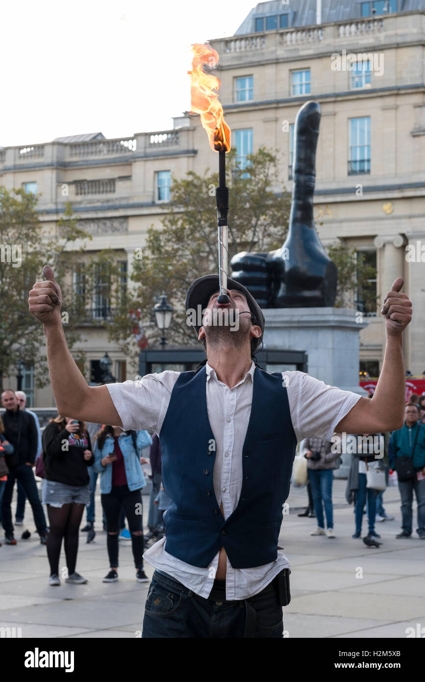 Londres, Royaume-Uni. 30 septembre 2016. Un artiste de rue effectue dans un contexte de la nouvelle œuvre d'art en bronze appelée "Vraiment bien" par l'artiste David Shrigley sur l'affichage à Trafalgar Square. Le public peut profiter de voir une main géante d'un mètre de long, sept de façon disproportionnée le pouce. L'œuvre est destiné à apporter un sentiment de positivité pour le spectateur. Crédit : Stephen Chung / Alamy Live News Banque D'Images