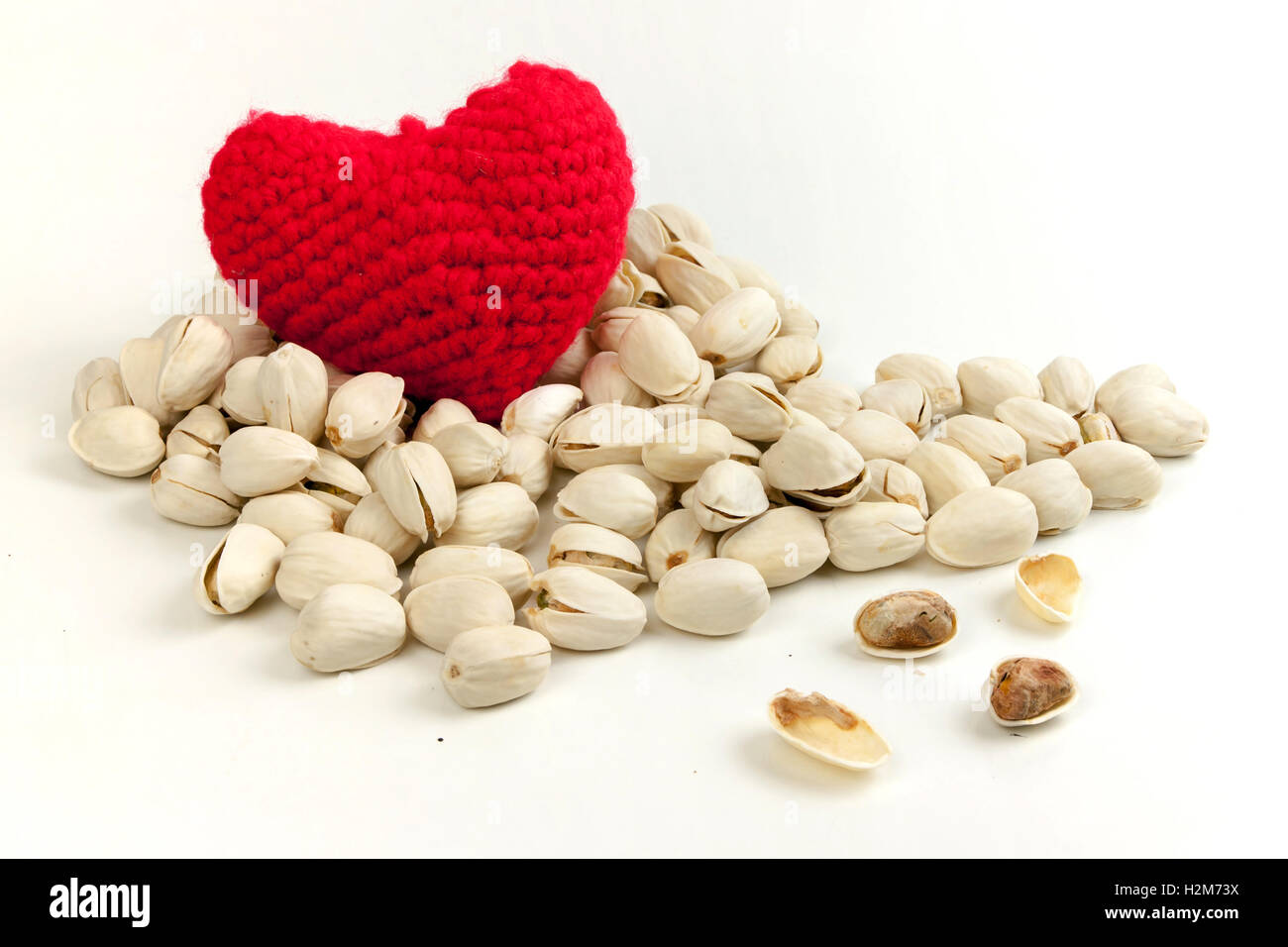 Pistaches rôties avec fil à tricoter pour former un cœur rouge sur fond blanc, une alimentation saine et la nutrition Banque D'Images