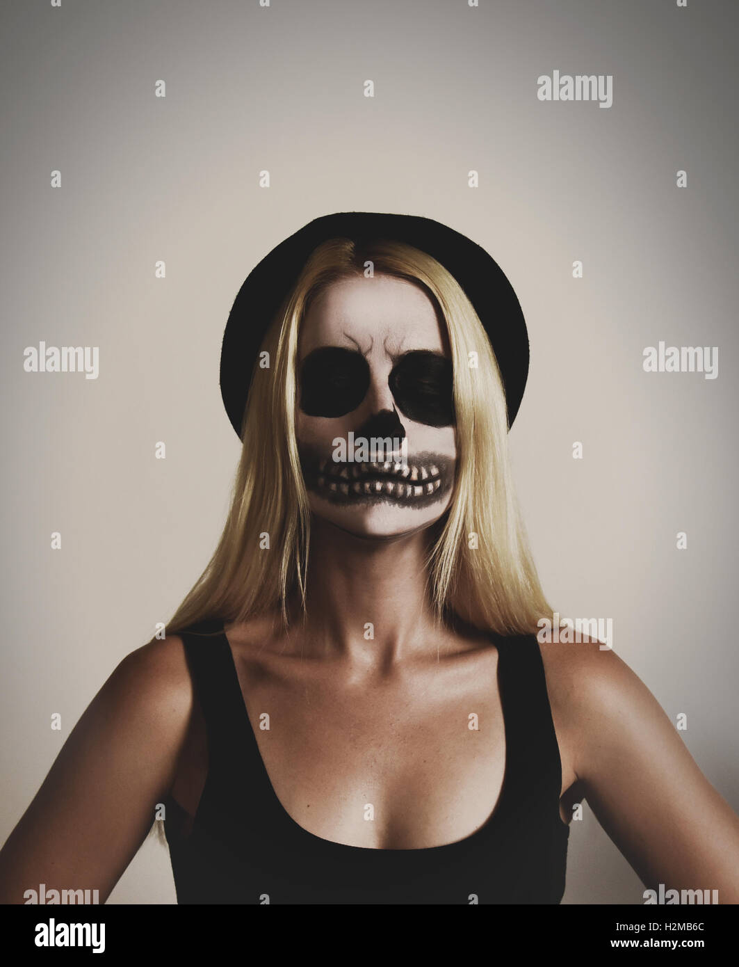 Une jeune femme porte un masque effrayant skelton un miroir avec de la peinture noir et blanc sur un arrière-plan pour un isolé costum halloween Banque D'Images