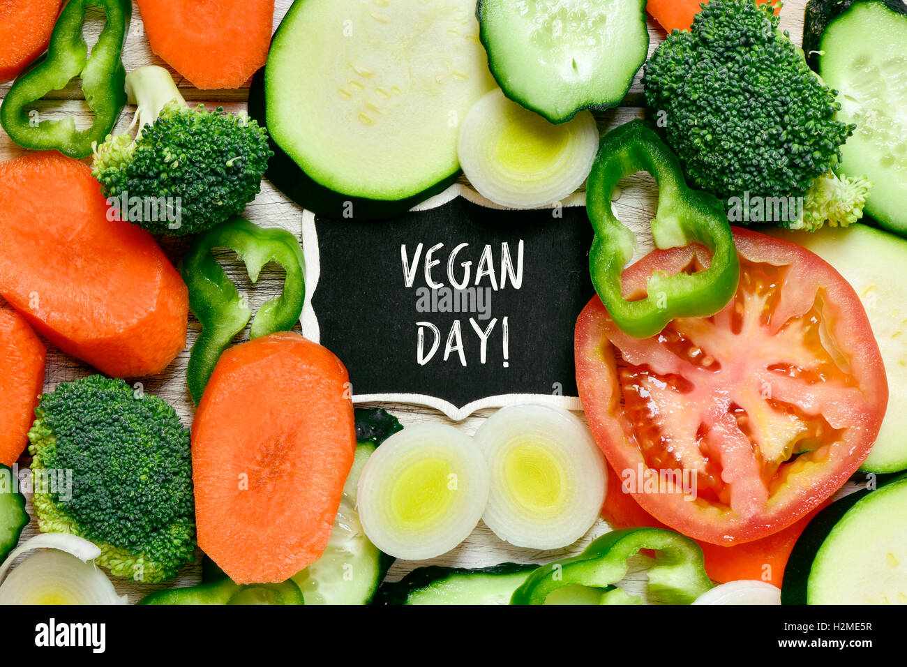 Capture d'un grand angle d'une surface en bois plein de différents légumes crus hachés et un tableau avec le texte écrit en vegan day Banque D'Images