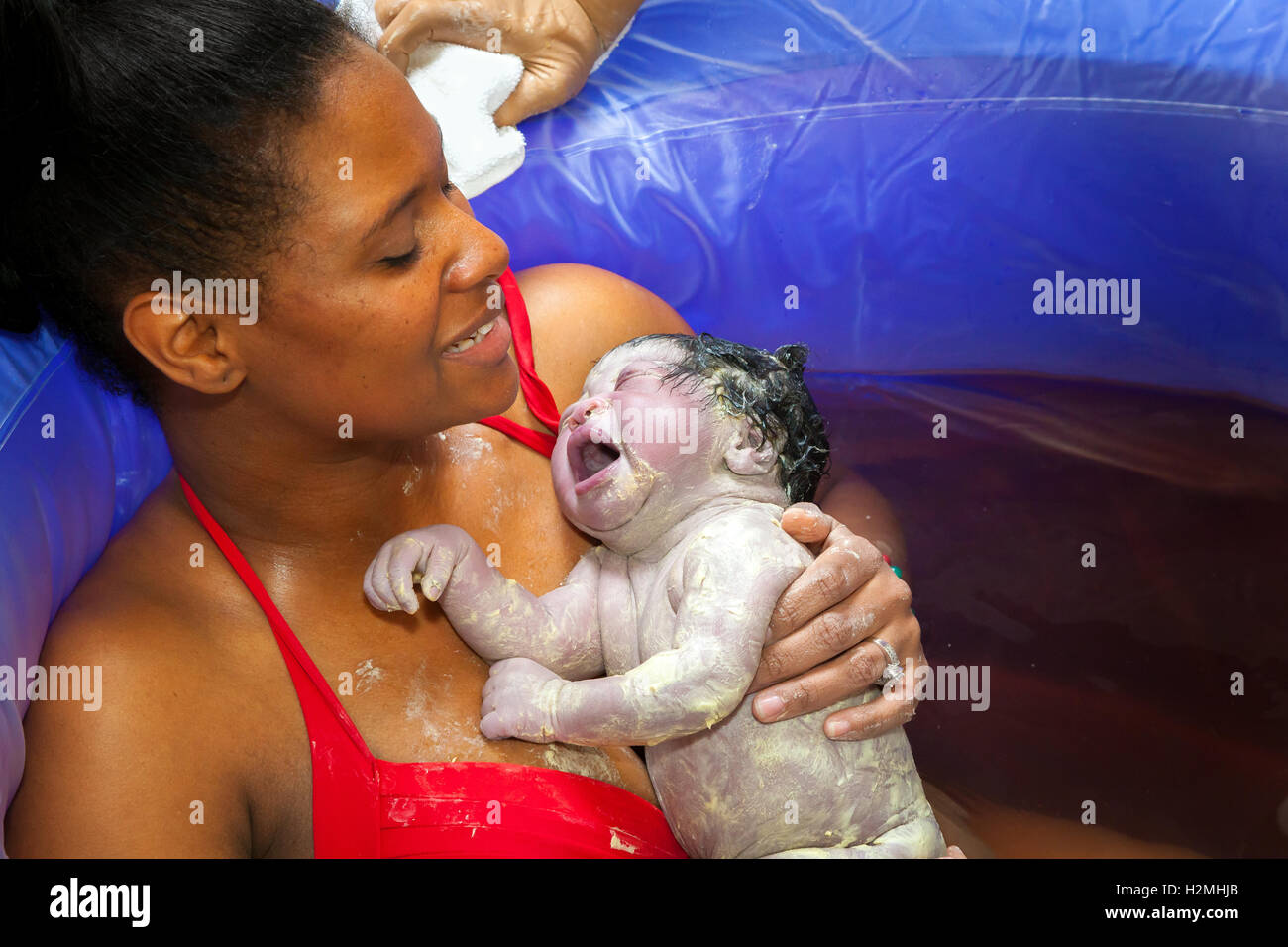 Un African American Woman Hold Crier Bebe Nouveau Ne Fille Dans Une Piscine D Accouchement Juste Apres L Accouchement Le Bebe Est Couvert De Photo Stock Alamy