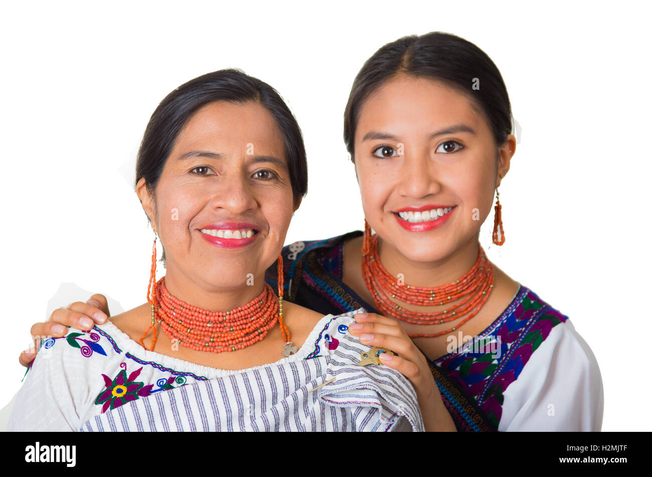 Belle hispanique mère et fille portant des vêtements traditionnelle des Andes, embrassant tout en se posant en interaction heureusement ensemble pour l'appareil photo, l'arrière-plan blanc studio Banque D'Images