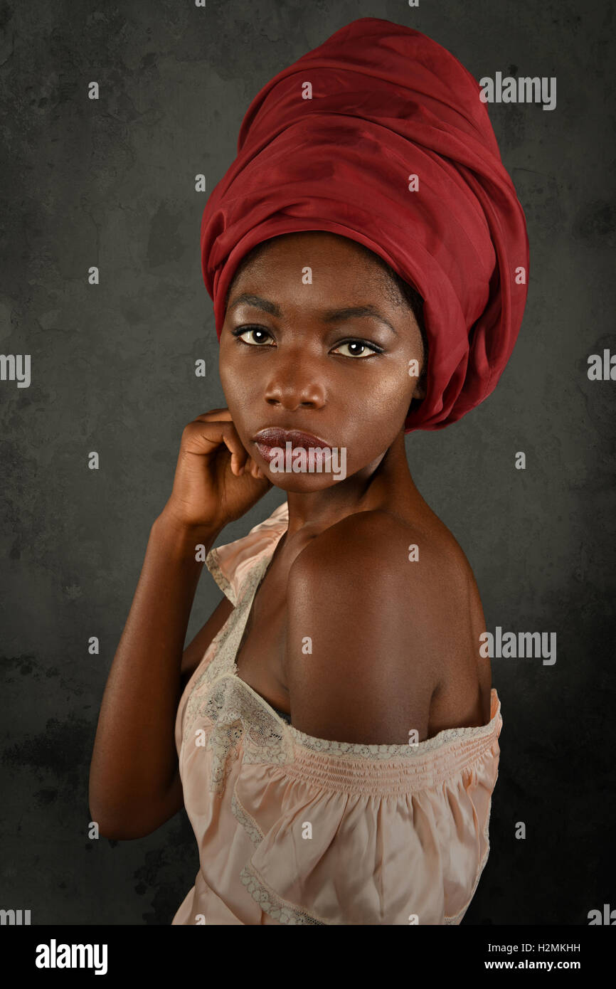 Jeune femme africaine avec turban rouge sur fond gris Banque D'Images
