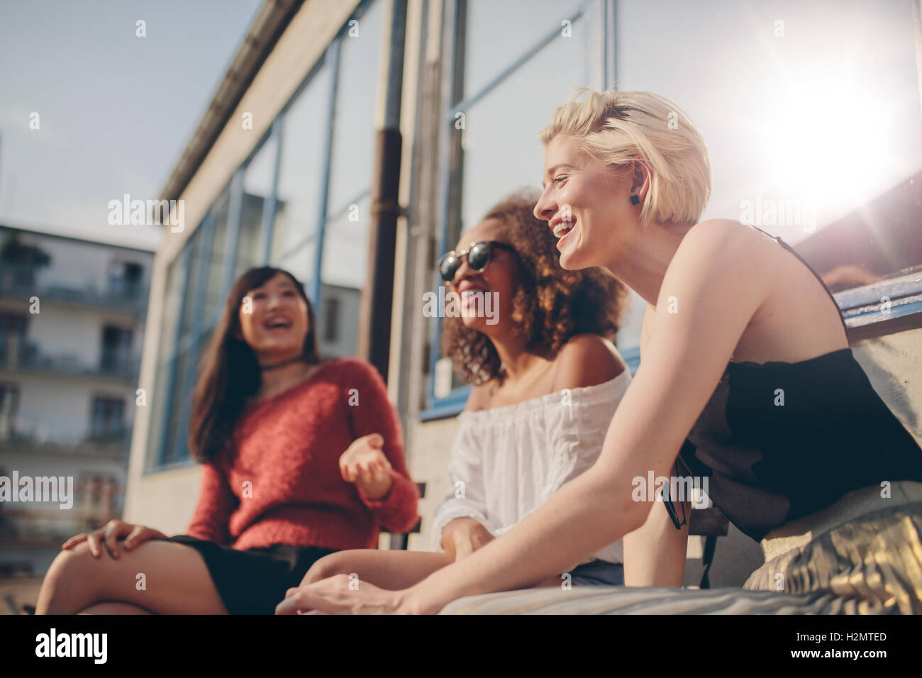 Groupe d'amies s'amuser tout en étant assis au café en plein air. Trois jeunes femmes assises à une terrasse et profiter de la conversation. Banque D'Images