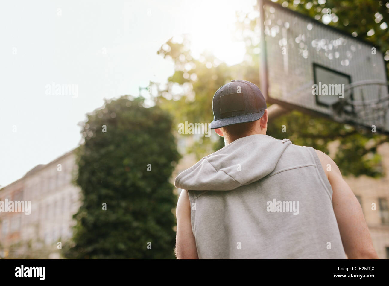 Vue arrière Vue d'un joueur de streetball debout sur un terrain de basket-ball en plein air sur une journée d'été. Banque D'Images