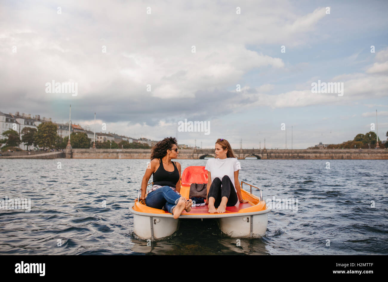 Tourné à l'extérieur de deux jeunes femmes amis assis en face de pédalos. Amis adolescents profiter de la navigation de plaisance dans le lac. Banque D'Images
