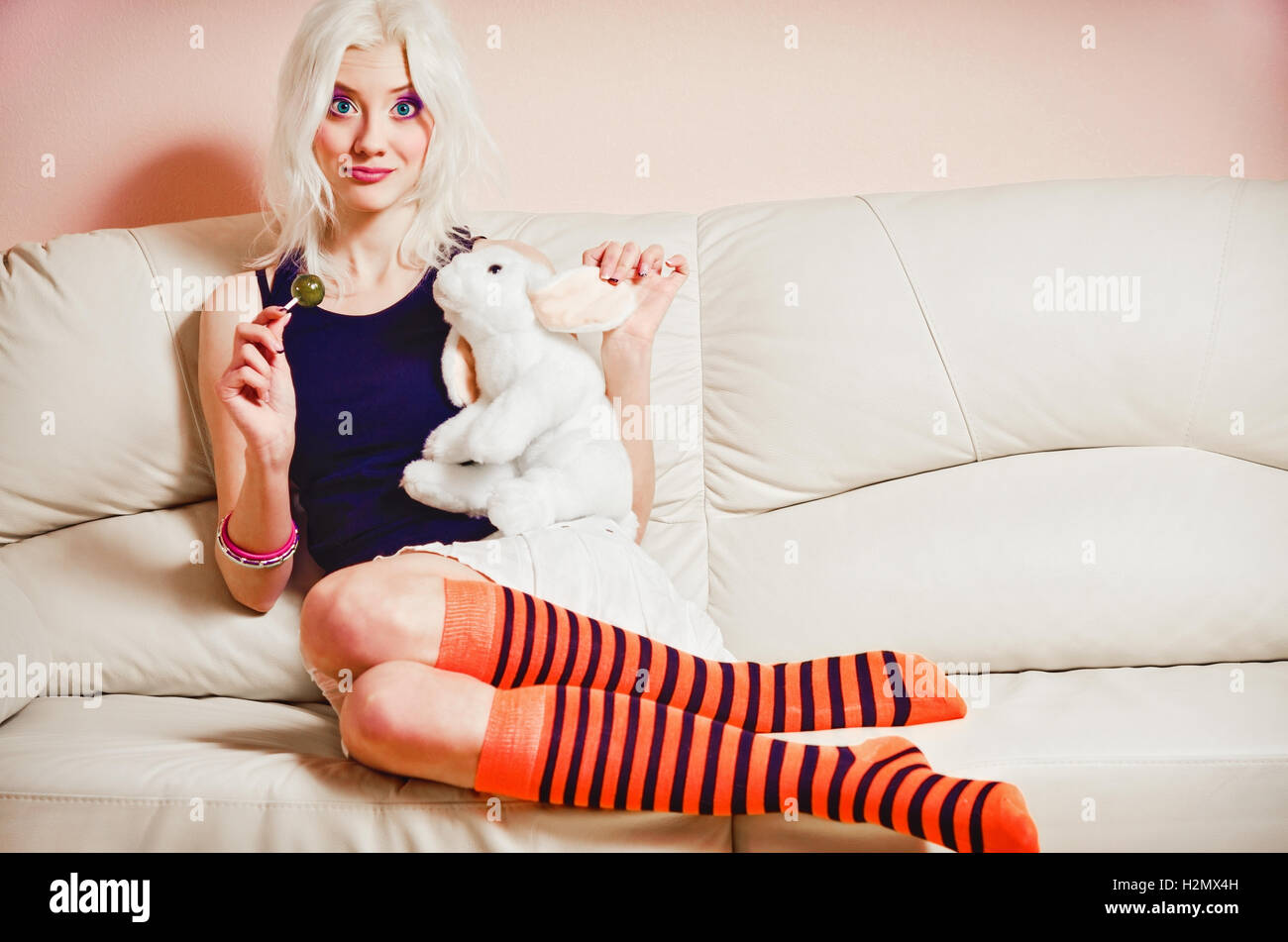 Closeup portrait of cute blonde girl avec des bonbons et lapin toy Banque D'Images