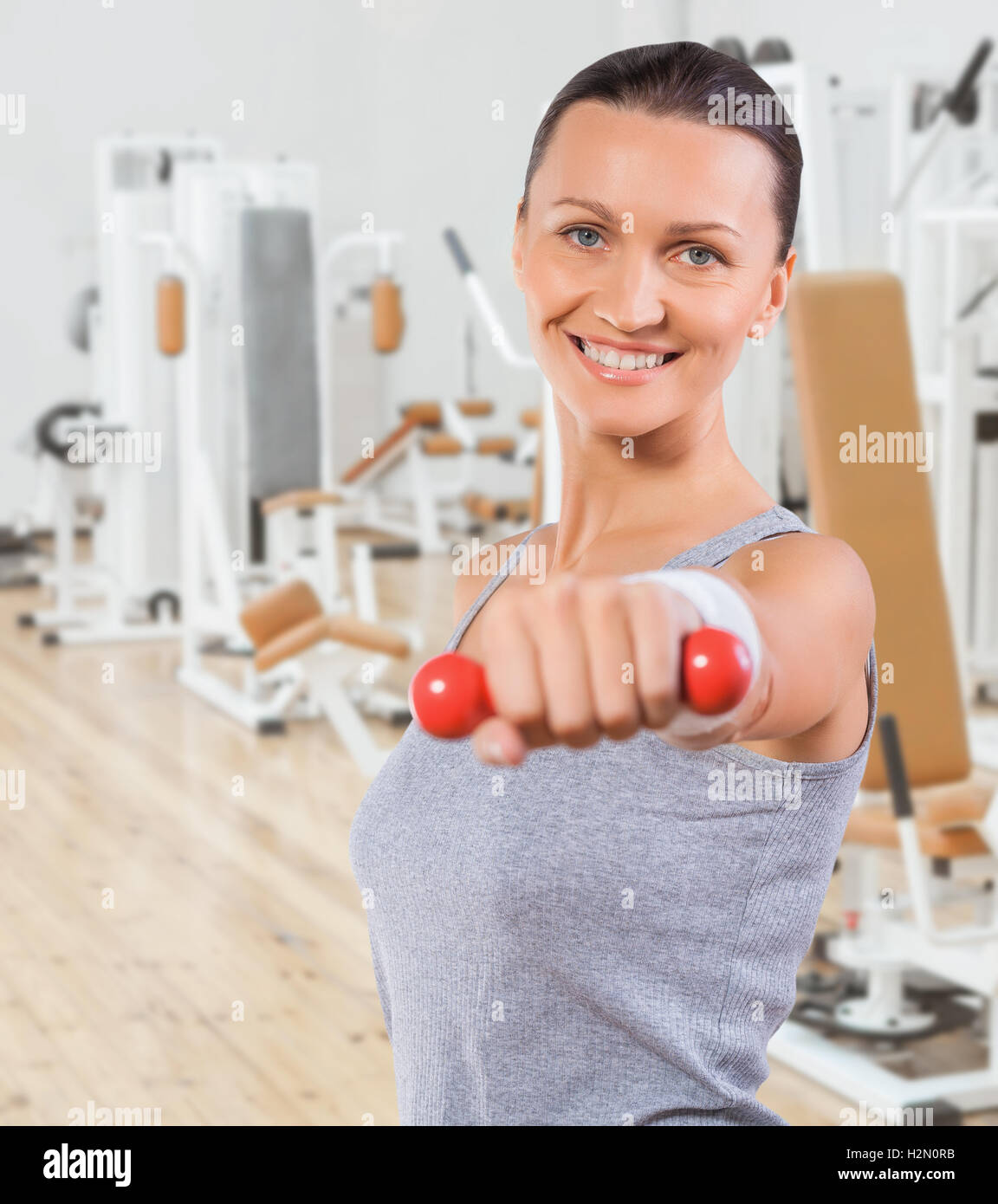 Belle petite sportive avec haltère dans la salle de sport Banque D'Images