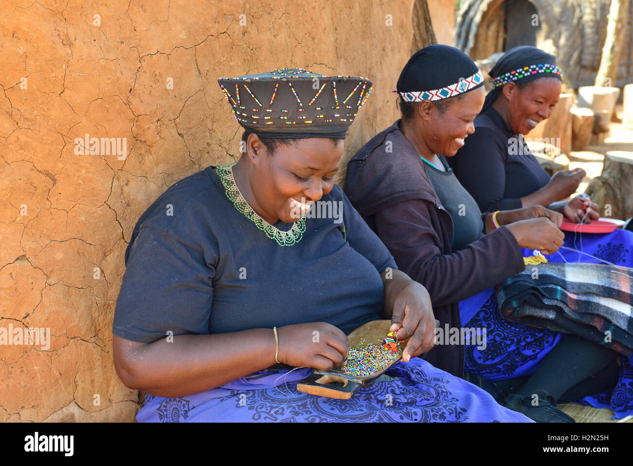 Les femmes zoulou traditionnel des décorations en perles à Shakaland Cultural Village, tout en cherchant l'ombre d'une rondavel, KwaZulu-Natal, Afrique du Sud Banque D'Images