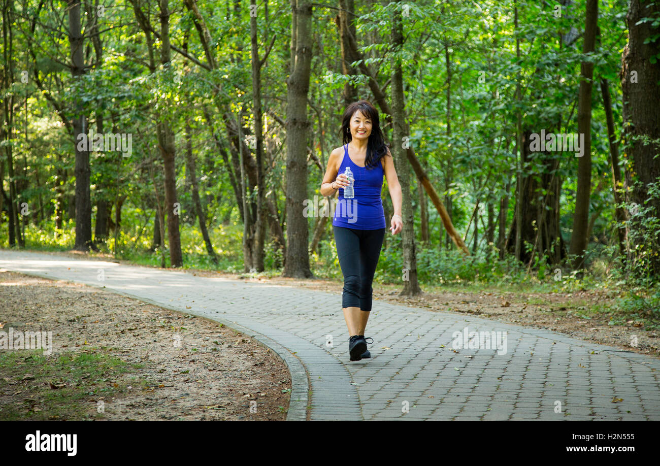 Femme asiatique américaine marchant sur un sentier de parc Banque D'Images