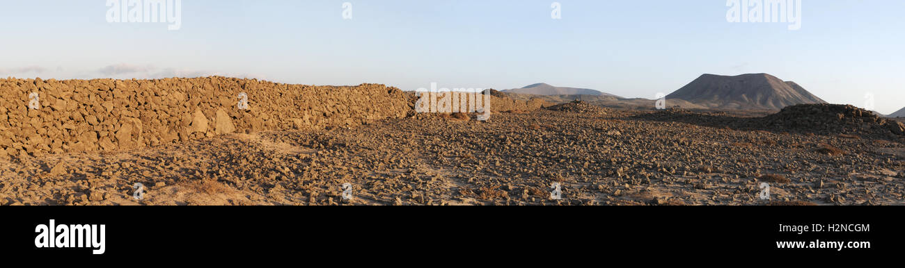 Fuerteventura, Îles Canaries, Afrique du Nord, Espagne : mur en pierre et la montagne au coucher du soleil sur le chemin de terre Majanicho à Corralejo Banque D'Images