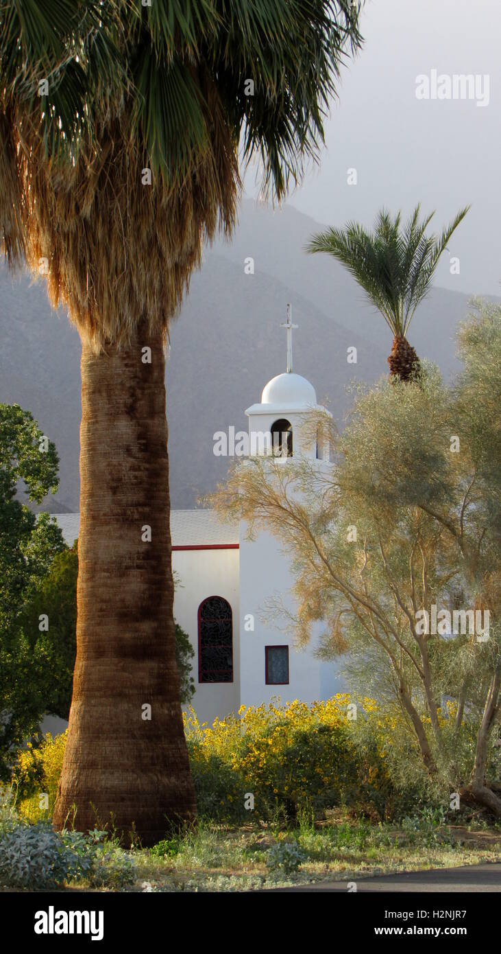 Blanc catholique église pittoresque avec Bell Tower et entouré de palmiers de la Californie un cotinus et tournesol Banque D'Images