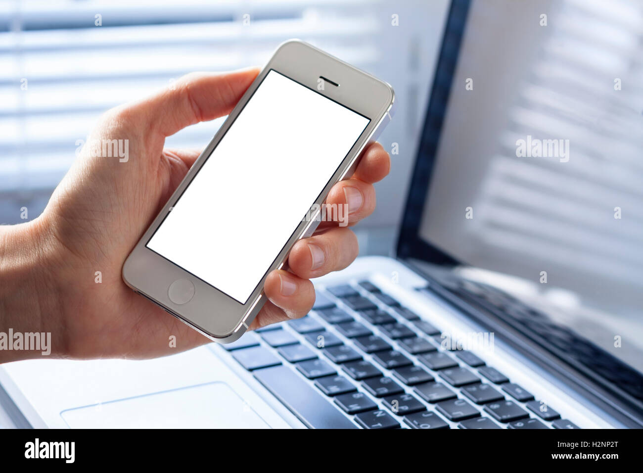 Smartphone avec écran blanc dans la main de business woman working in office with laptop Banque D'Images