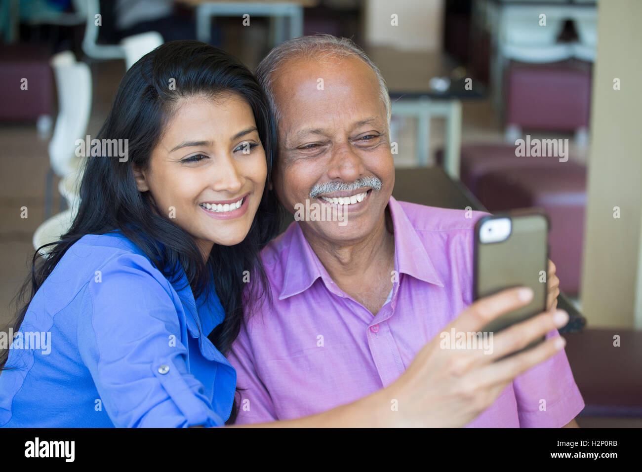 Closeup portrait heureux homme âgé en chemise rose et lady in blue top en tenant ensemble, l'intérieur isolé selfies arrière-plan. Banque D'Images
