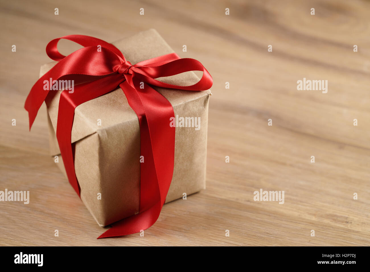 Brown paper gift box with red ribbon bow on wooden table Banque D'Images