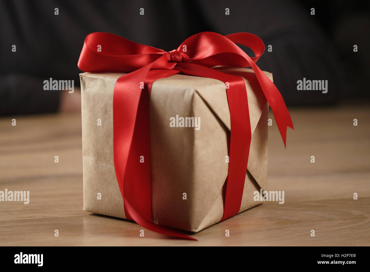 Brown paper gift box with red ribbon bow on wooden table Banque D'Images