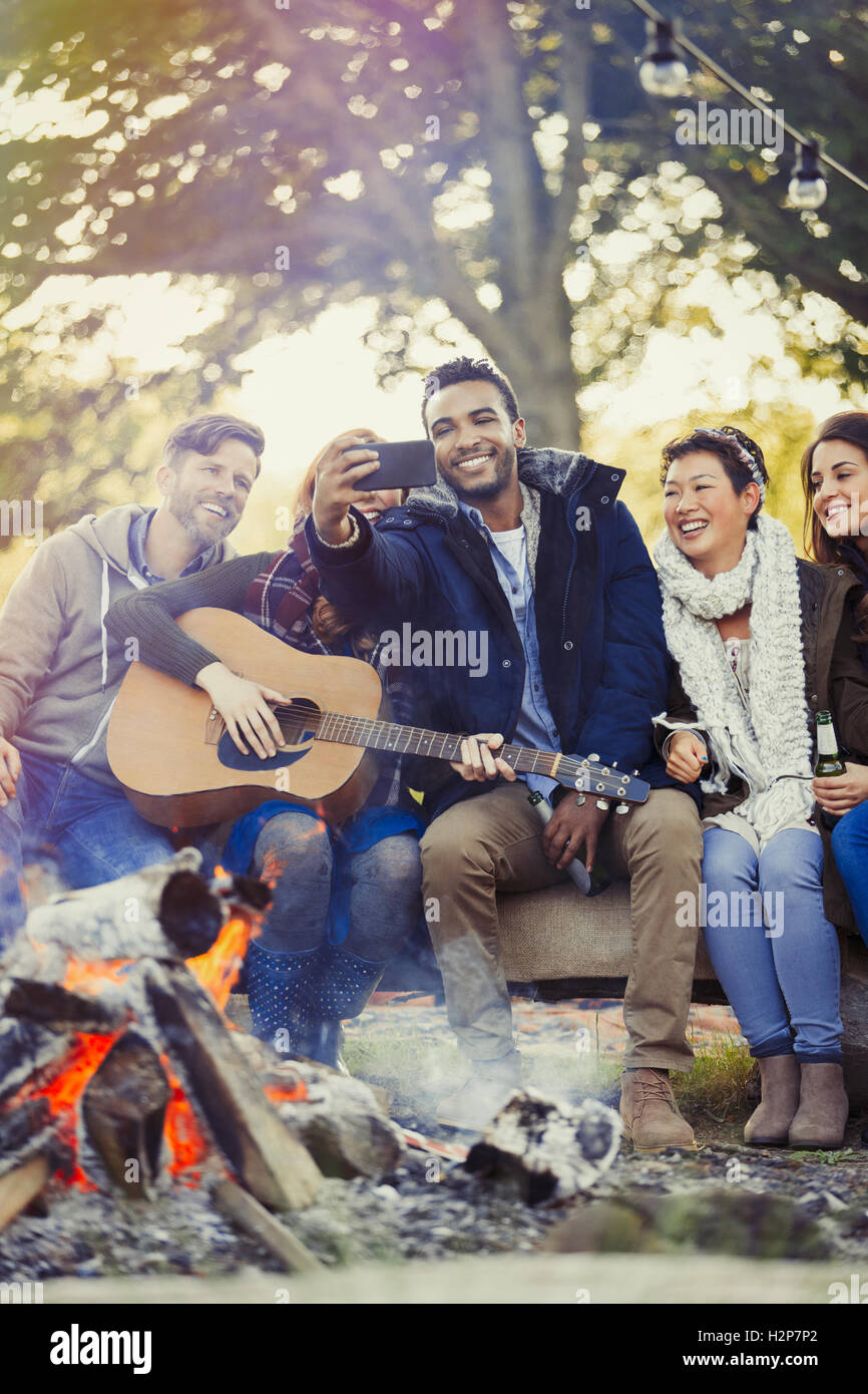 Amis avec guitare en tenant avec selfies téléphone appareil photo au camp Banque D'Images