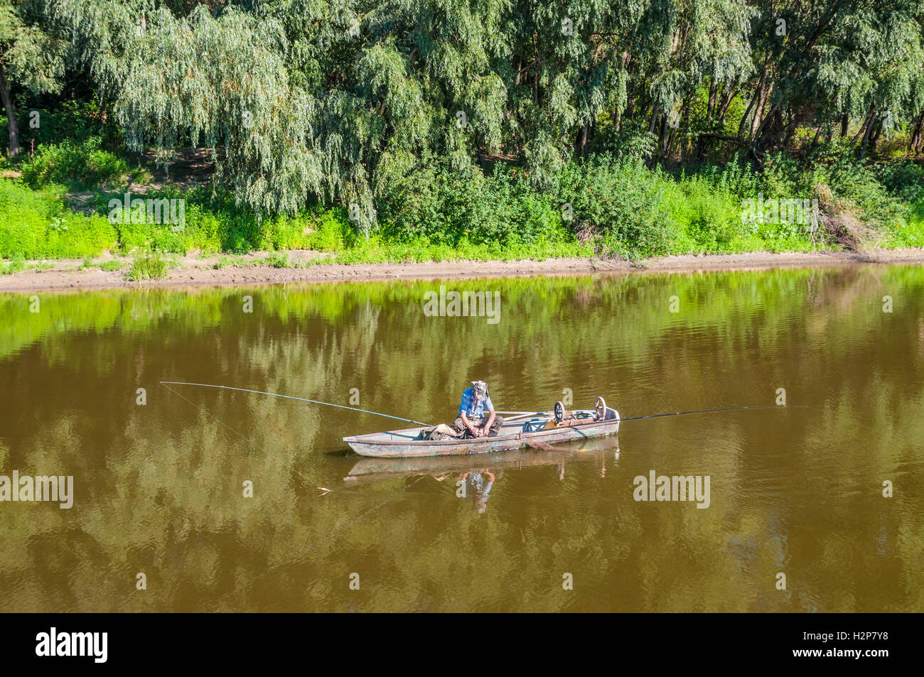 Un pêcheur dans un bateau en bois sur la rivière Desna à proximité de Chernihiv, Ukraine. Banque D'Images