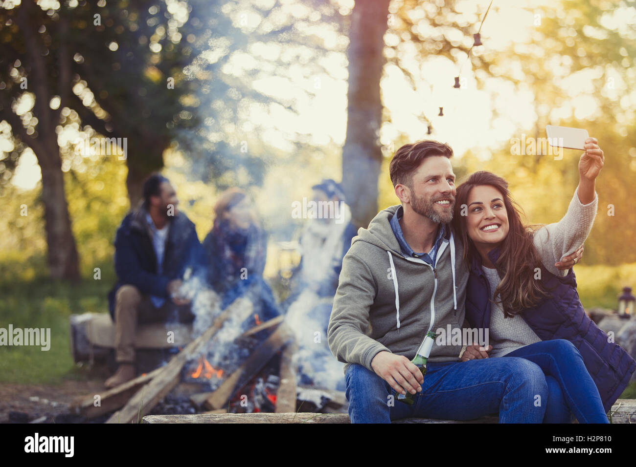 Smiling couple en tenant avec selfies téléphone appareil photo à proximité de camp Banque D'Images