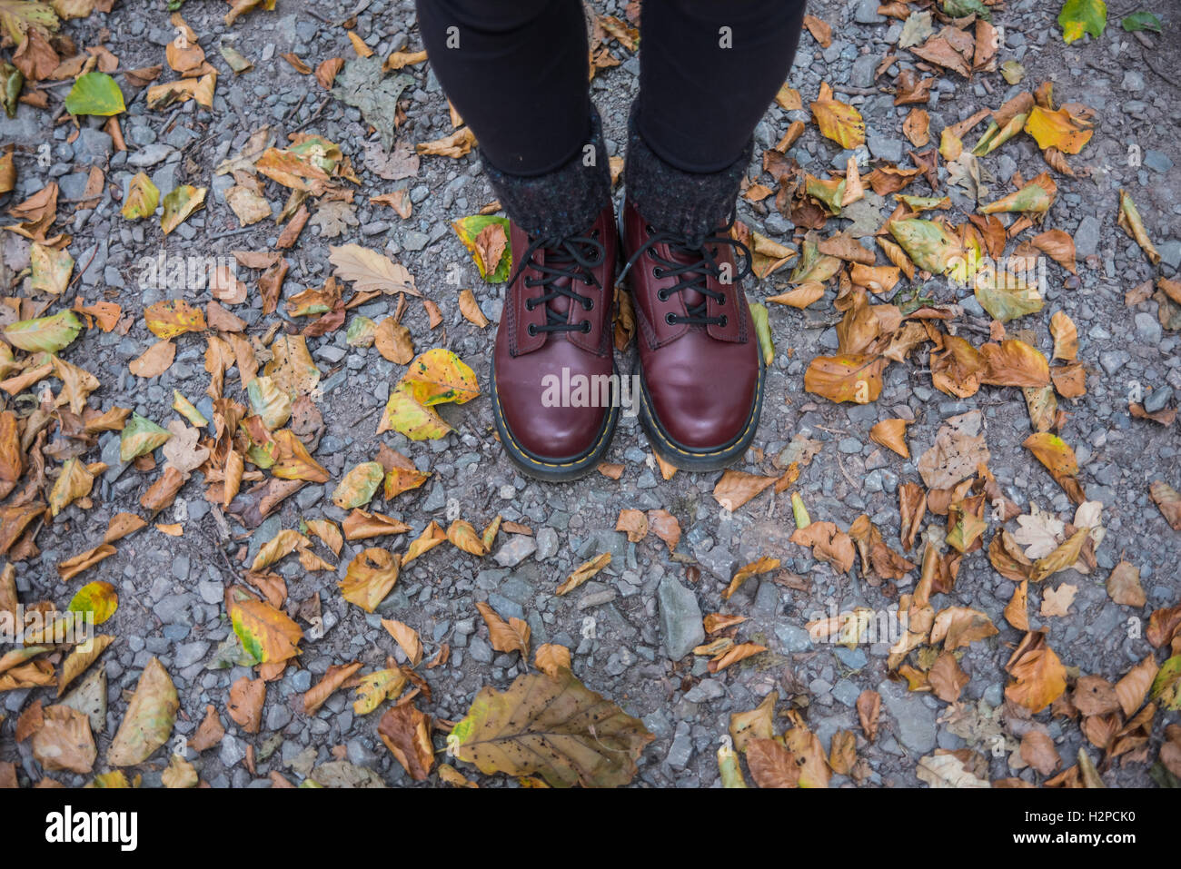 Femme debout dans les feuilles d'automne avec doc marten boots Banque D'Images